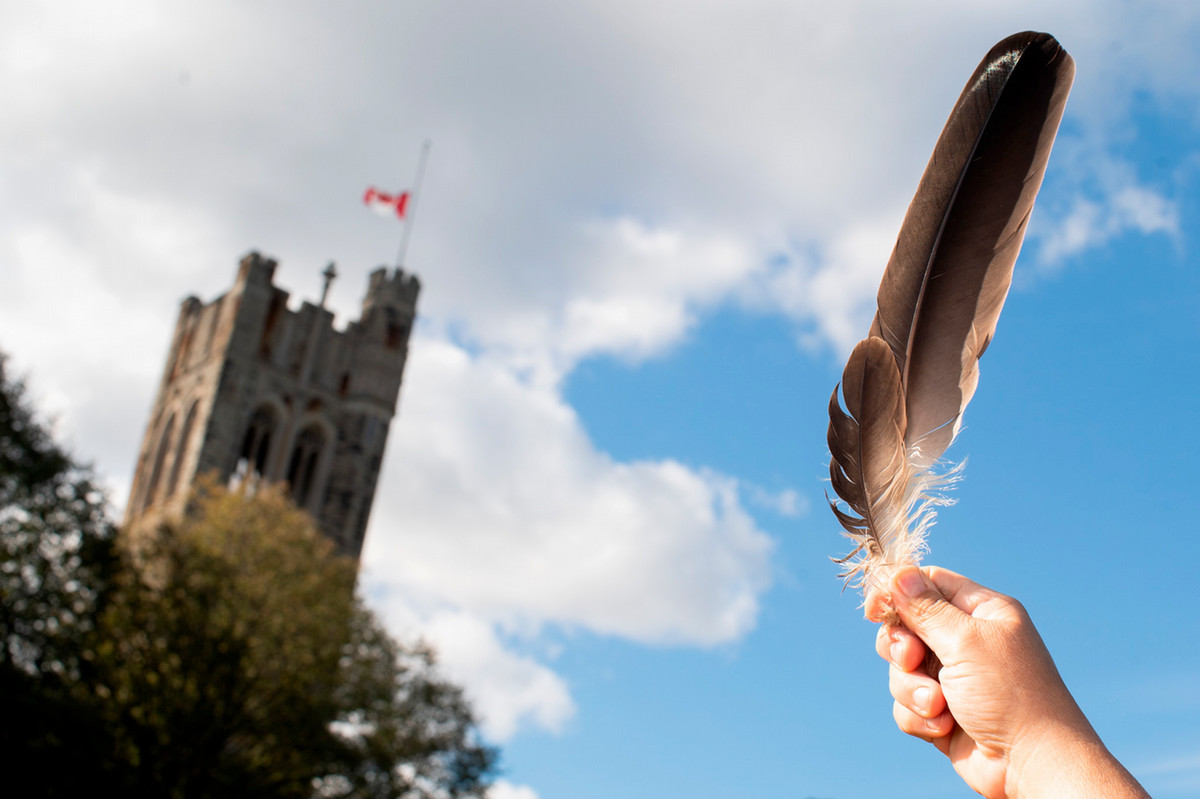 Western University building, a hand holding up a feather towards the Canadian flag